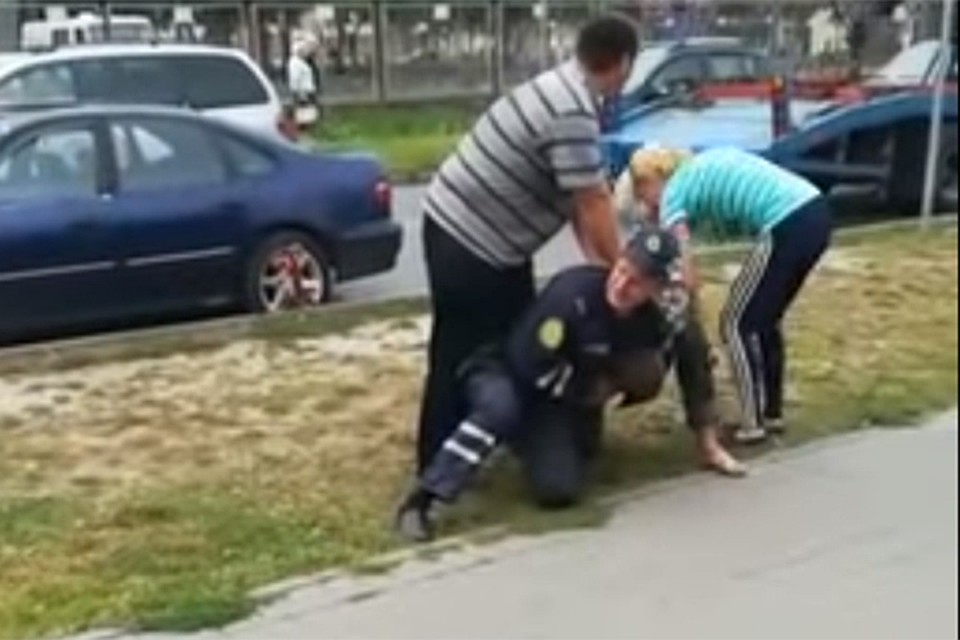 На помощь сотруднику ГАИ пришел водитель эвакуатора, а на помощь мужчине - прохожие. Фото: кадр из видео.