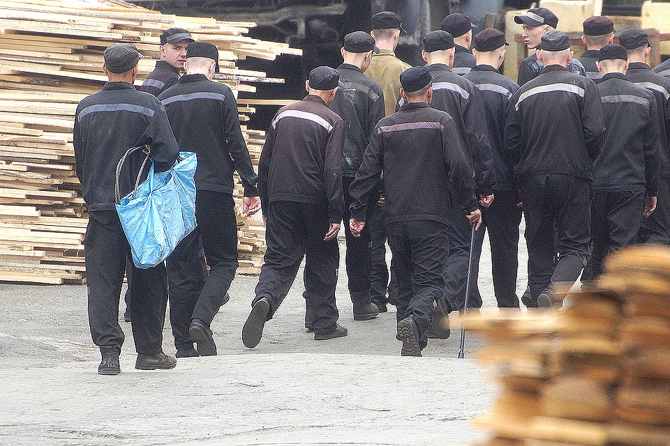 Осужденные идут строем по производственной территории колонии.