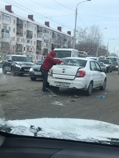 В Омске после ДТП таксист начал спешно сдирать наклейки с машины