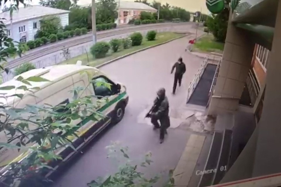 Первый нападавший несколько раз стреляет на поражение, второй хватает сумку.