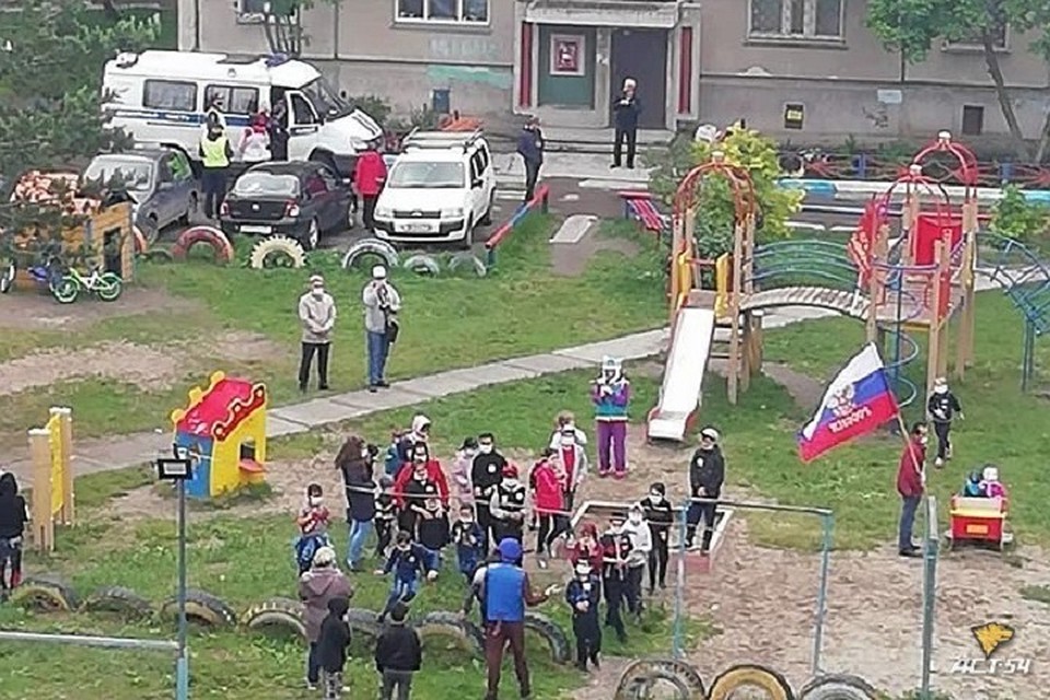 Дети и их родители танцевали во дворе дома, стоя слишком близко друг к другу.