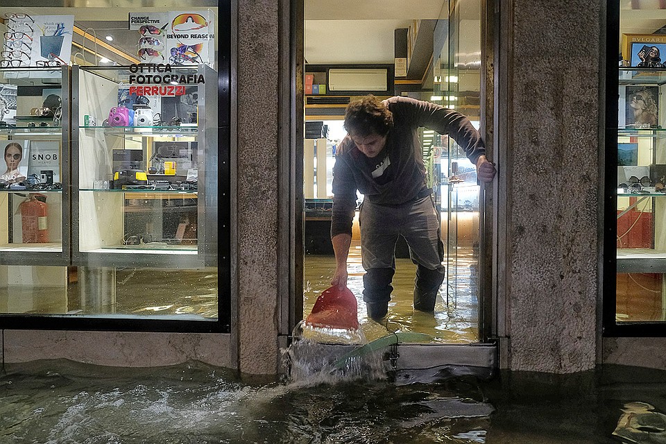 Работник лавки оптики пытается спасти свой магазин от воды. Фото: REUTERS