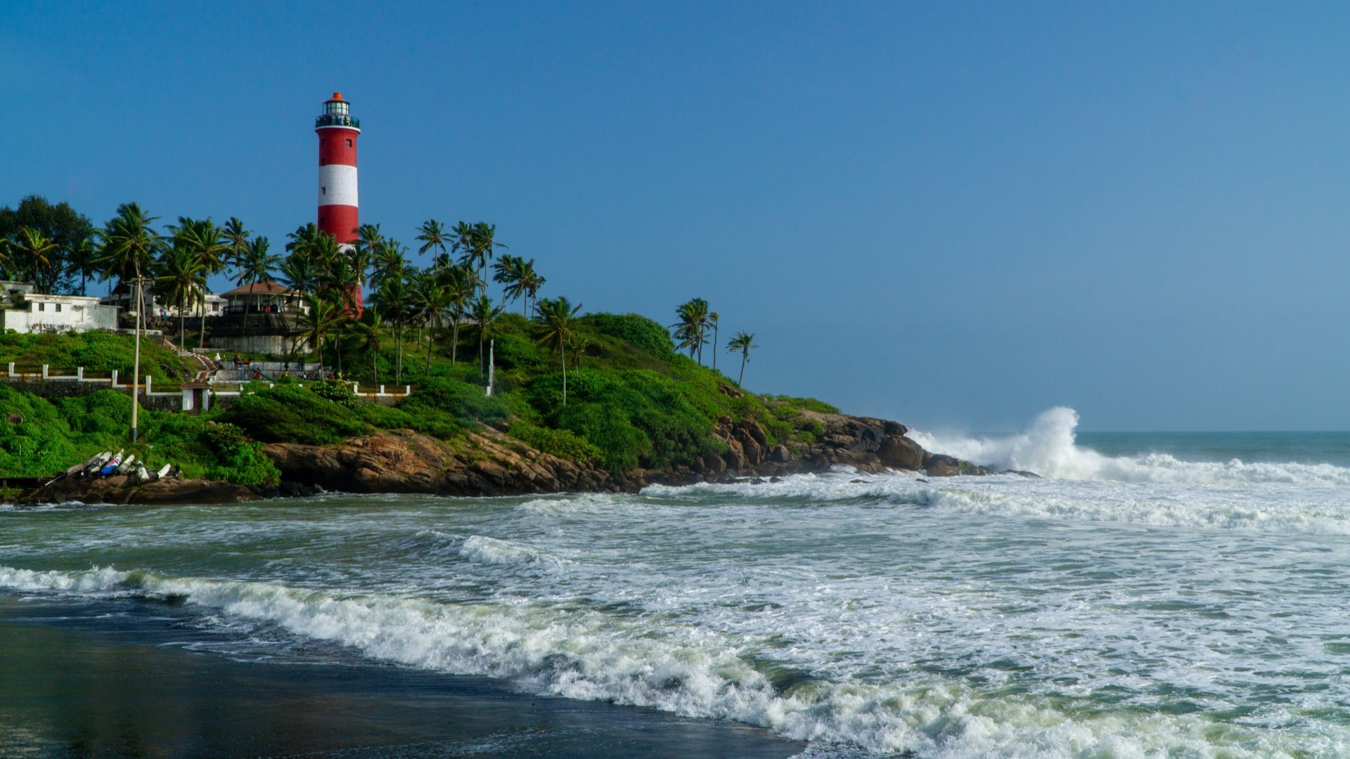 Пляж Ковалам в штате Керала с маяком на скалистом берегу.